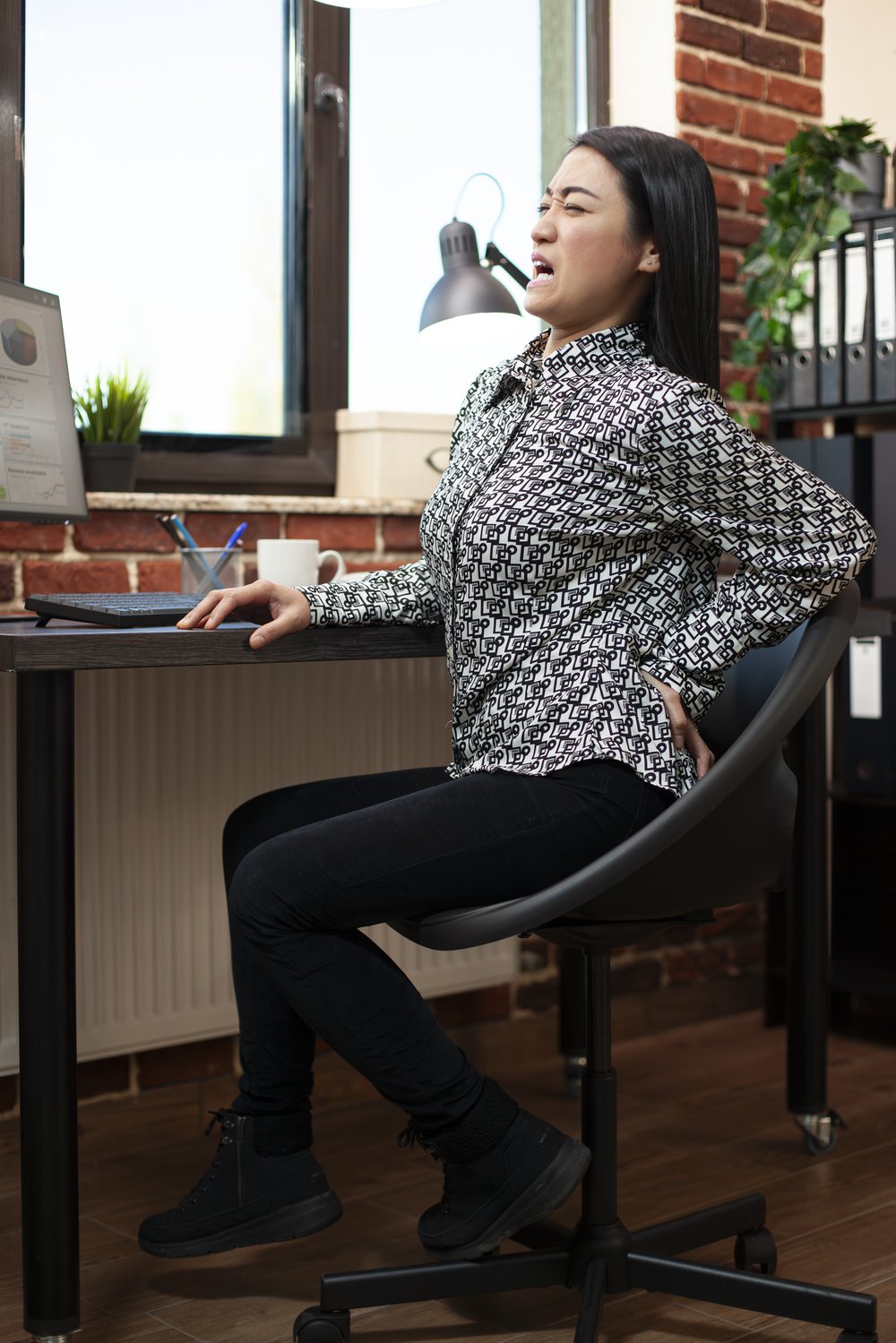 Office worker experiencing lower back pain from poor desk posture