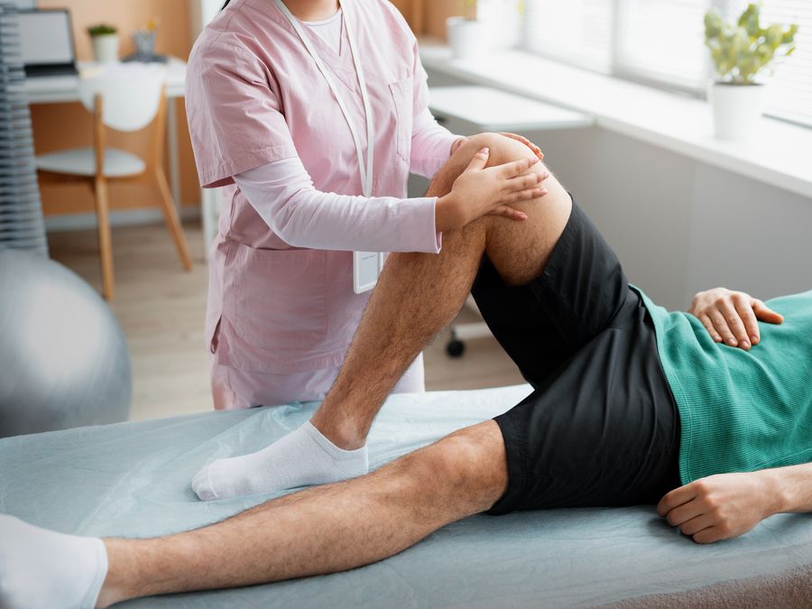 Physiotherapist mobilising a patient's knee joint on a treatment couch