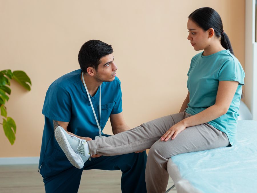 Clinician supporting a patient through post-operative leg rehabilitation